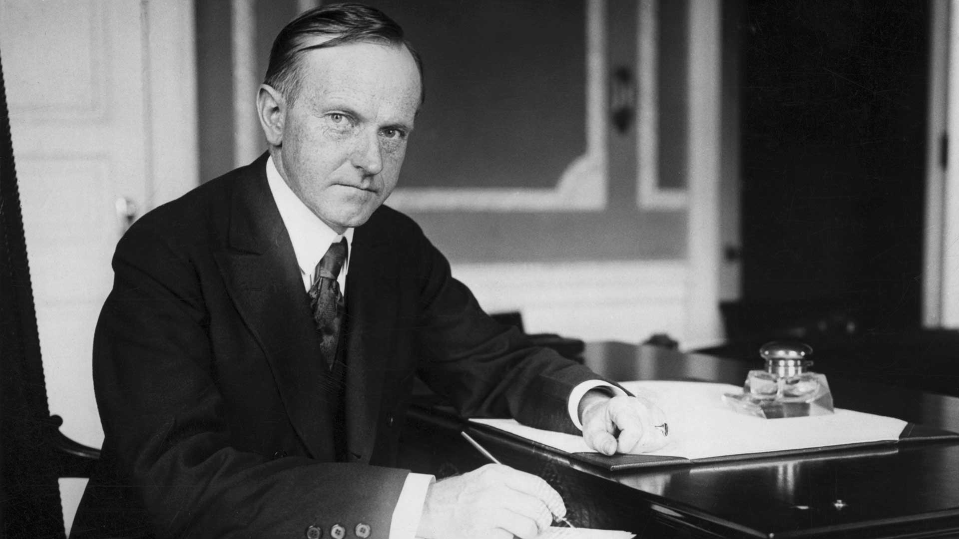 Calvin Coolidge (1872-1933), 30th President, sitting at his desk.